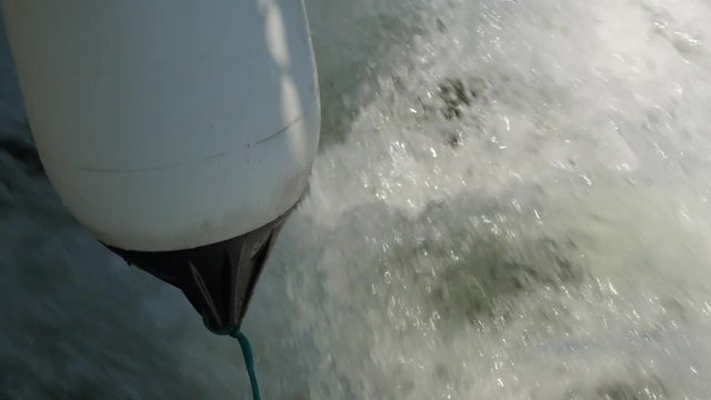 Slow motion of a boat with a bouy cruising through the ocean water