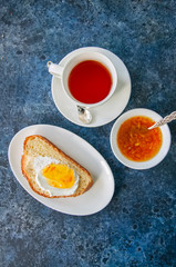 Slice of homemade sesame seeds challah bread  with jam, glass of milk and a cup of tea on a white background.
