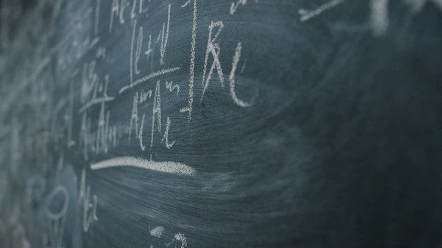 Hand Holding Chalk and Writing Complex and Sophisticated Mathematical Formula/ Equation on the Blackboard.