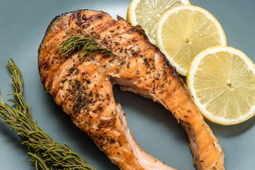 Salmon fillet. Grilled salmon with herb and lemon on plate. Fish roasted on a wooden background.