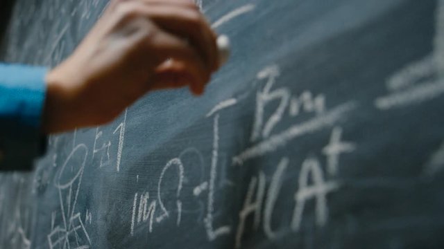 Hand Holding Chalk and Writing Complex and Sophisticated Mathematical Formula/ Equation on the Blackboard.
