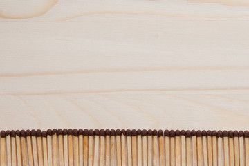 wooden unburned matches with stylized heads laid out in an even row against the background of a light brown tree
