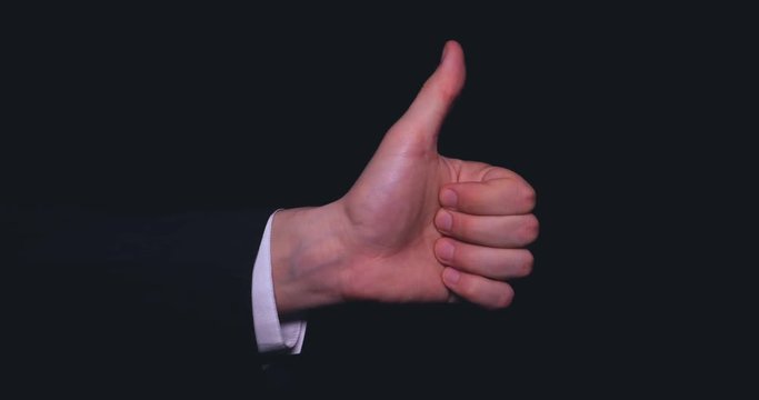 Businessman in suit, thumb up (like), black background.