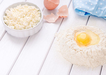 Baking cake in rustic kitchen - dough recipe ingredients eggs, flour, milk, butter, sugar on white planked wooden table from above. Background layout with free text space