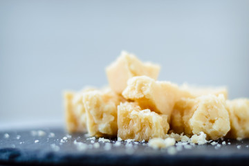 Parmesan sliced into pieces on white background