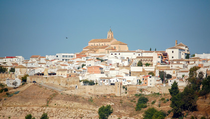 The Church of Santa Maria la Mayor between whitewashed houses and the blue sky - Baena, Andalusia,...