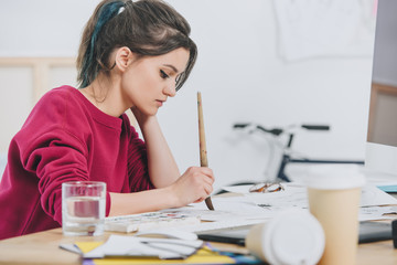 Attractive young girl drawing sketches by working table