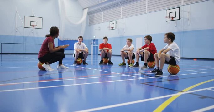 4k, A female African American coach talking to a group of elementary school basketball team.