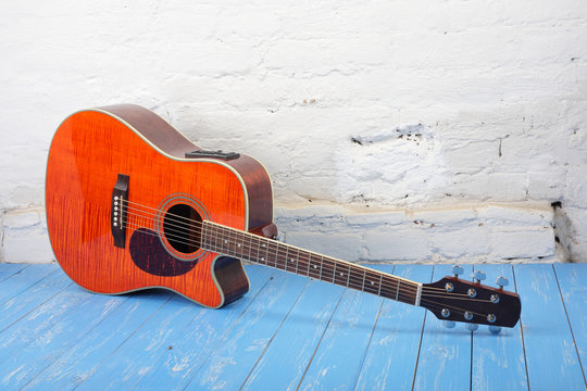 Musical instrument - Orange flame maple acoustic guitar white brick background