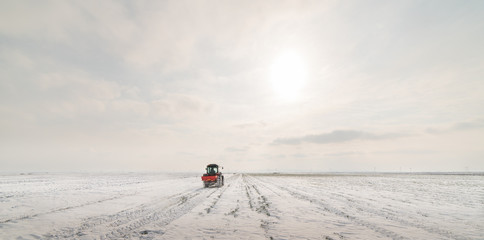 Farmer with tractor seeding - sowing crops at agricultural fields in winter