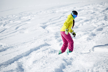 Fototapeta na wymiar Photo of athlete girl wearing helmet and mask, snowboarding from snowy mountain slope