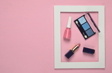 Female cosmetics in a white frame on a pink pastel background. Shadows for make-up, lipstick, nail polish. Minimalist trend. Top view. Copy space..