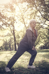 Naklejka na ściany i meble Senior woman in sport clothing working exercise for legs.