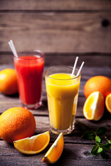 Orange juice in glass with mint, fresh fruits on wooden background