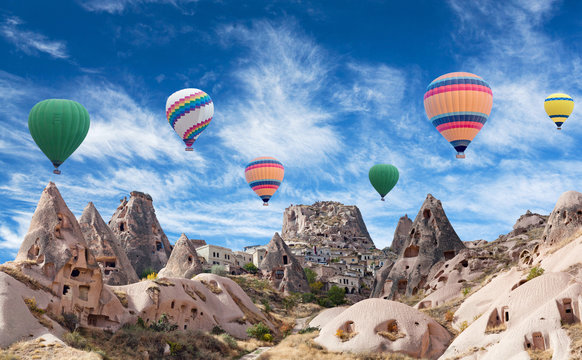 Uchhisar fortress and colorful hot air balloons flying over valley in Cappadocia, Anatolia, Turkey