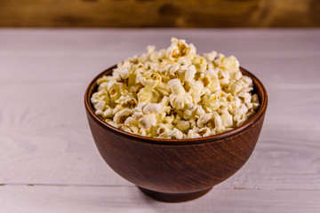 Ceramic bowl with popcorn on wooden table