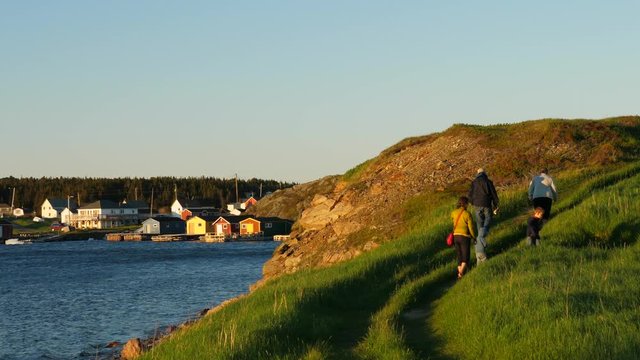 Slow motion shot of a family walking along the ocean at sunset