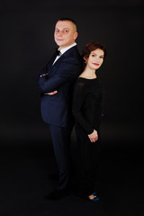 Elegance woman in black evening dress with man in suit posed on studio isolated on black. Duet couple of two.