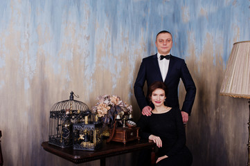 Elegance woman in black evening dress with man in suit posed on studio near retro phone. Duet couple of two.