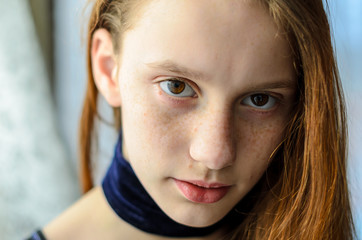 red-haired girl teenager with deep brown eyes, freckles natural beauty without makeup looks straight