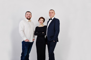 Fototapeta premium Elegance woman in black evening dress with two man in suit posed on studio isolated on white. Trio band.