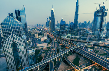 Aerial view over big highway interchange and skyscrapers in Dubai, UAE, at sunset. Scenic cityscape. Toned travel and architectural background.