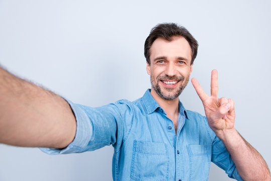 People rest relax weekend freetime journey resort concept. Close up portrait of joyful glad friendly bearded with beaming smile guy showing peace symbol taking selfie isolated on gray background