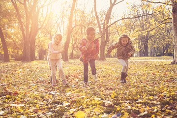 Naklejka premium Three active little girls in park.
