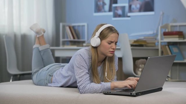 Teen girl listening to music, communicating in social networks, using laptop