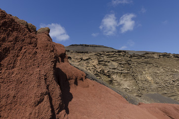 Fototapeta premium Red volcanic rocks in El Golfo Lagoon a popular tourist destination on Lanzarote, the Canary Islands