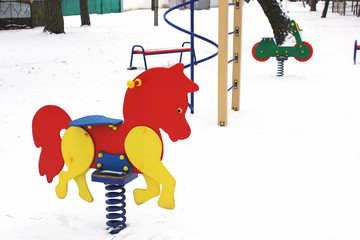 Children's swing. Winter. Playground. Wooden horse