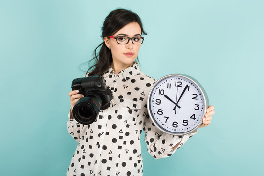 Young woman with camera and clocks