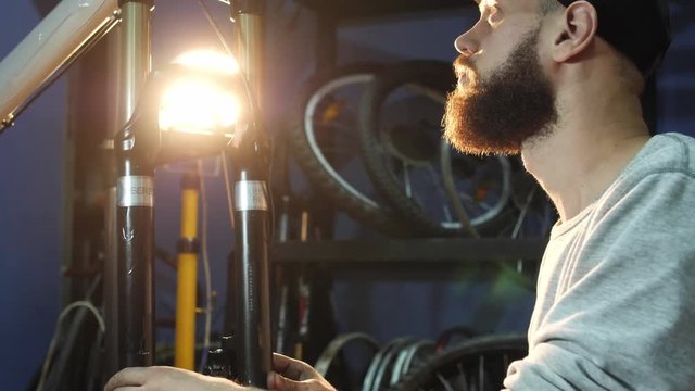 Close-uo of man bike mechanic assembles a mountain bike in his workshop