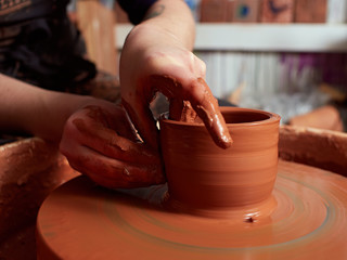 production process of pottery.  Forming a clay mug on a potter's wheel.
