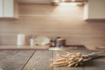 Blurred and abstract kitchen background. Wooden tabletop with wheat and defocused modern kitchen for display your products.