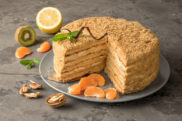 Homemade layered honey cake. Russian and ukrainian traditional delicacy. Near it lie fruits and walnuts.