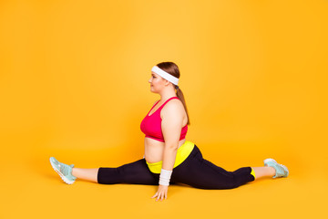 Young woman in exercise clothes does a forward split