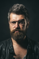 Fototapeta premium Stylish fashion man, confident attractive serious handsome hipster wears black leather jacket and stylish eyewear. Cool seductive man in leather jacket and fashionable glasses.People and style concept