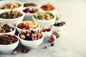 Assortment of dry tea in white bowls. Tea types backgound: green, black, floral, herbal, mint, melissa, ginger, apple, rose, lime tree, fruits, orange, hibiscus, raspberry, cornflower, cranberry