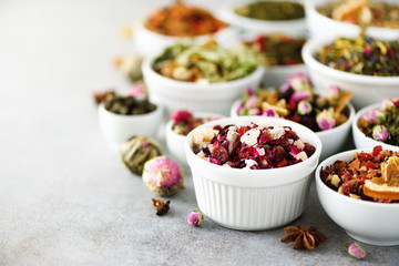 Assortment of dry tea in white bowls. Tea types backgound: green, black, floral, herbal, mint, melissa, ginger, apple, rose, lime tree, fruits, orange, hibiscus, raspberry, cornflower, cranberry