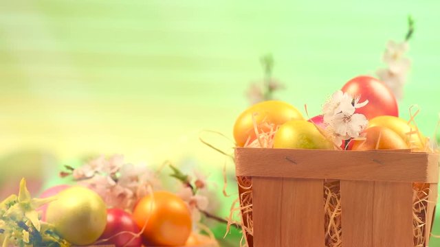 Easter holiday scene. Easter painted colorful eggs and spring flowers in a basket on a table rotated over green background. 4K UHD video 3840X2160
