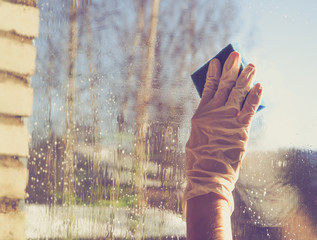 Female hand  cleaning window with blue rag and spray detergent. Spring cleanup, housework concept
