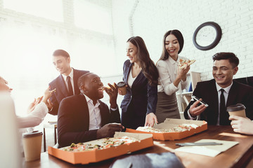 The office staff eat pizza and drink coffee in the business office.