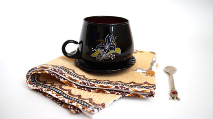 .black cup filled with cocoa on a napkin, next to a small spoon