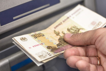 Men Hand Using Russian 100 rubles cash. Russian text 