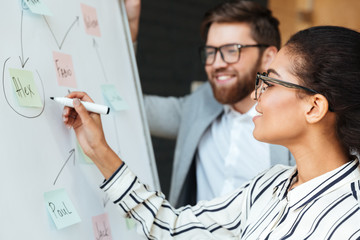 Happy young colleagues write something