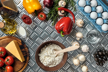 Food ingredients and spices for cooking pizza. Mushrooms, tomatoes, cheese, onion, oil, pepper, salt, egg, grater on metal background. Copy space. Top view