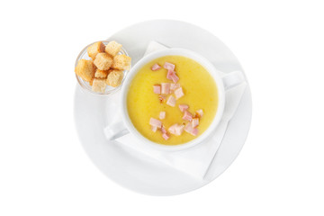 Soup puree, cream soup yellow with ham and croutons, dry bread. On a napkin in a white plate isolated white. Serving dishes in a cafe, restaurant, for a menu. View from above