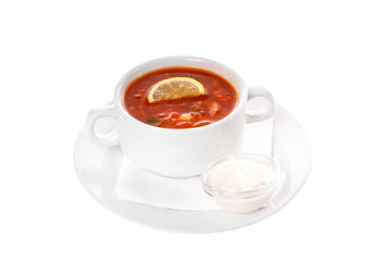 Solyanka, pickle with lemon and sour cream. On a napkin in a white plate isolated white. Serving dishes in a cafe, restaurant, for a menu. Side view