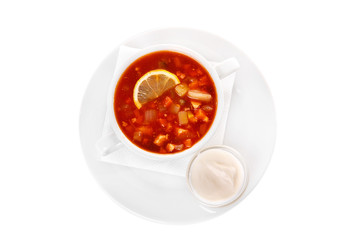 Solyanka, pickle with lemon and sour cream. On a napkin in a white plate isolated white. Serving dishes in a cafe, restaurant, for a menu. View from above